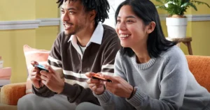 Dos personas jugando a Nintendo Switch 2 con los Joy-Con 2 en el sofá